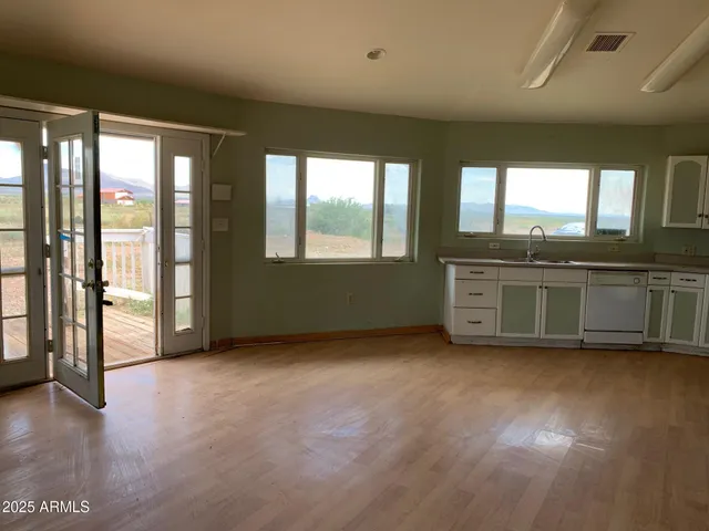 a view of an empty room with a window and wooden floor