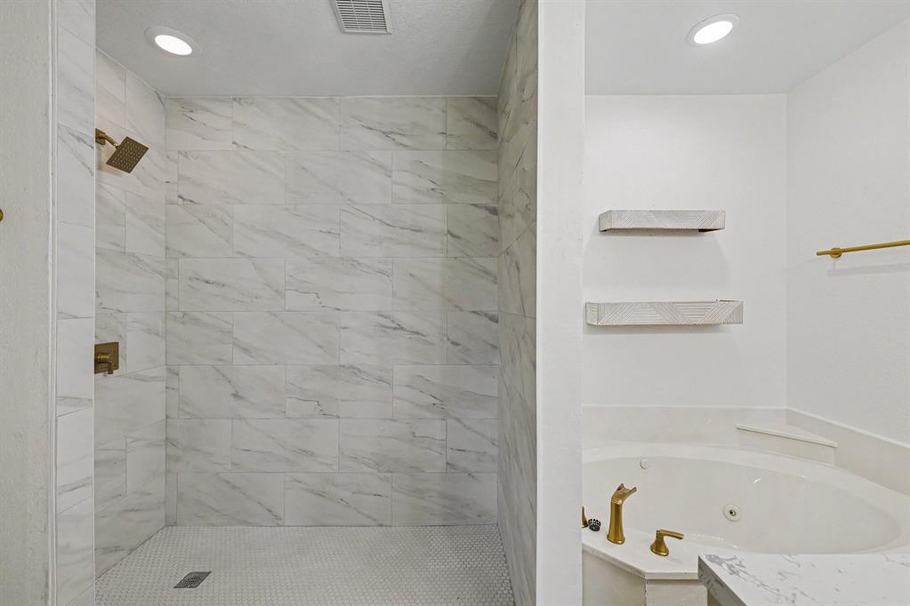 307 Dixon Street Terrell, TX 75160 - Photo 20 of 32 Spacious shower with large format marble-look tile walls and a mosaic tile floor, complemented by a corner jetted soaking tub