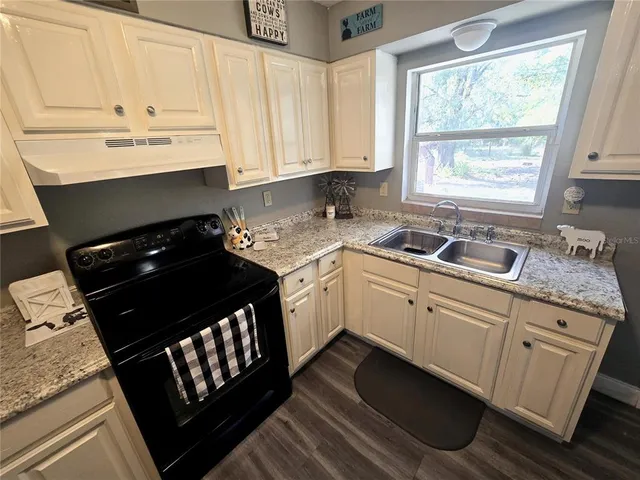 a kitchen with granite countertop a sink stove and cabinets