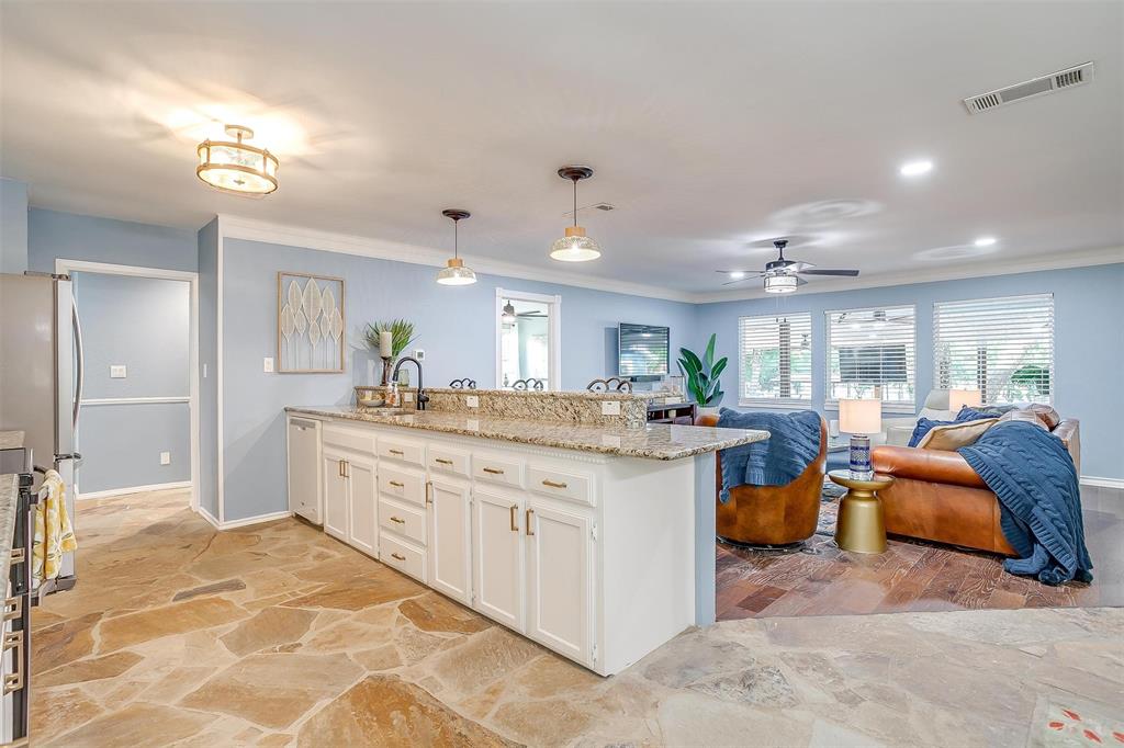 520 Deer Trail Gordon, TX 76453 - Photo 13 of 40 Kitchen with a peninsula, stone flooring, light stone countertops, white cabinets, and crown molding