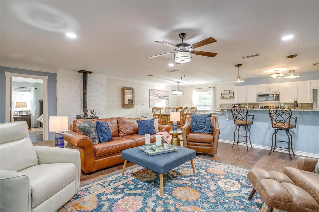 520 Deer Trail Gordon, TX 76453 - Photo 15 of 40 Living area featuring a wood stove, light wood-style floors, and ceiling fan