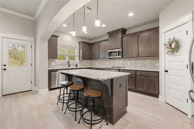 a kitchen with kitchen island granite countertop wooden floors and white cabinets