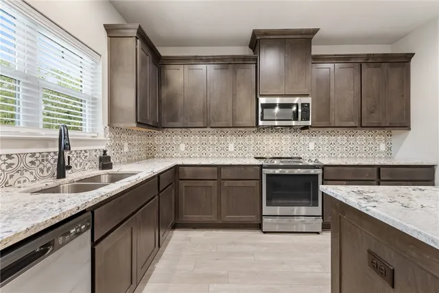 a kitchen with stainless steel appliances kitchen island granite countertop a sink stove and microwave
