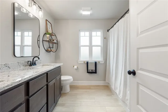 a bathroom with a granite countertop sink toilet and shower