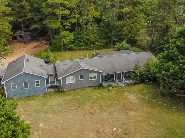 an aerial view of a house with swimming pool and large trees