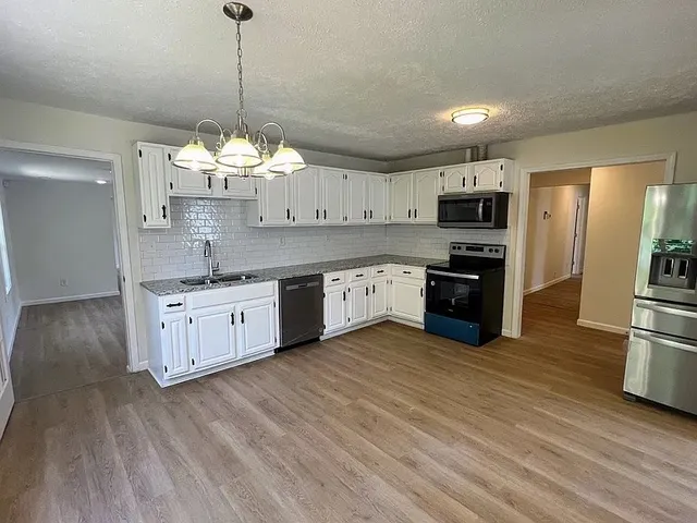 a kitchen with stainless steel appliances a sink a stove a refrigerator and cabinets