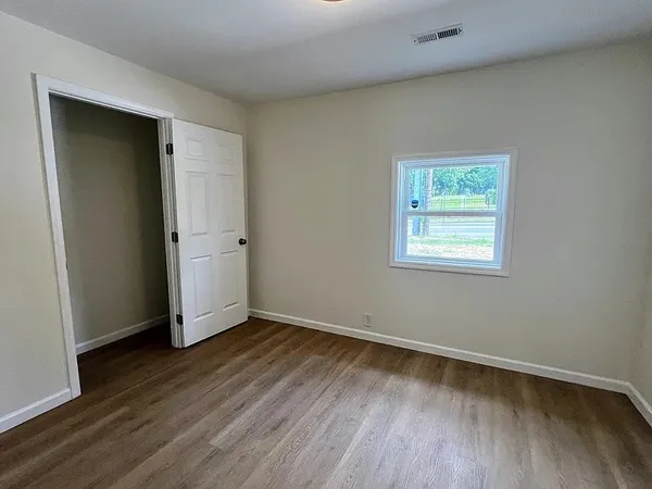 an empty room with wooden floor and closet