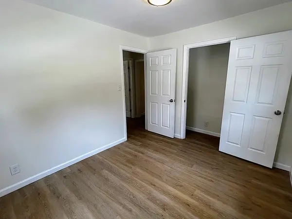 an empty room with wooden floor and closet area
