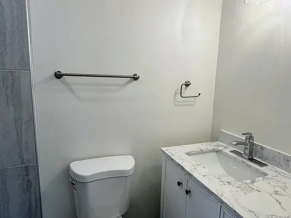 a bathroom with a granite countertop sink a toilet and a mirror