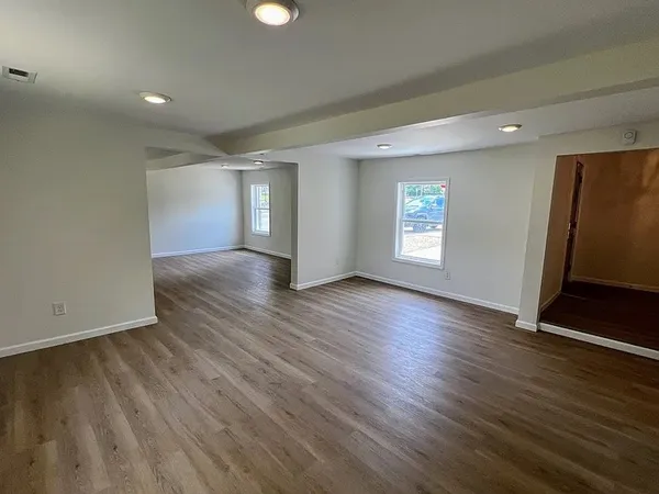 an empty room with wooden floor and window