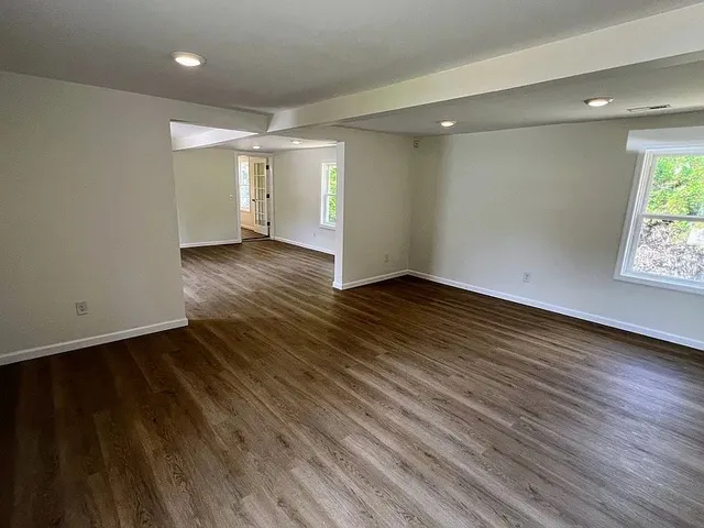 an empty room with wooden floor and windows
