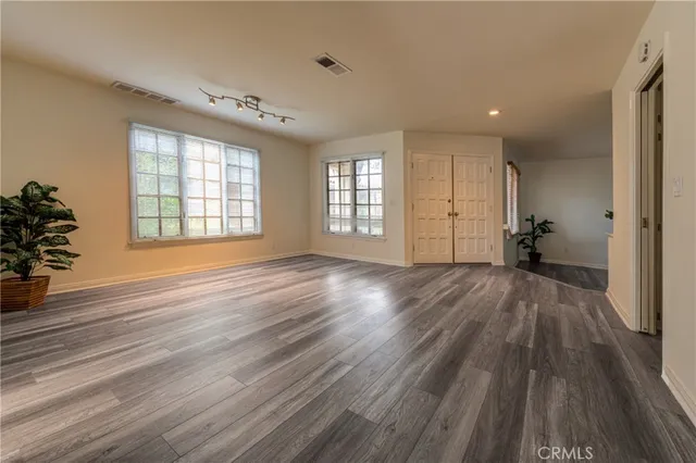 an empty room with wooden floor and windows