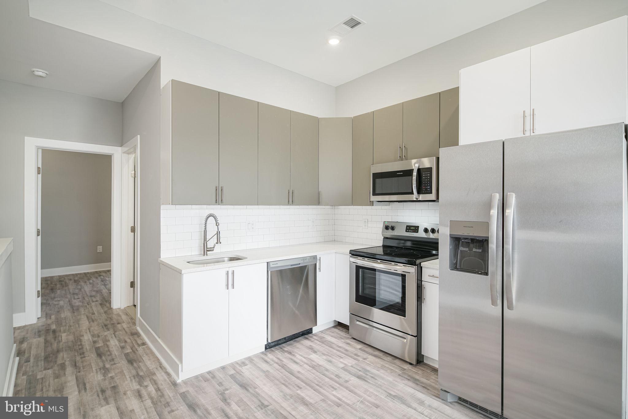 1443 North 8th Street, Unit 2 Philadelphia, PA 19122 - Photo 2 of 18 a kitchen with cabinets stainless steel appliances and wooden floor