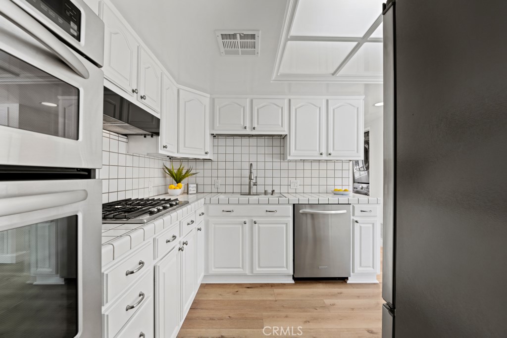 731 North Beachwood Drive Burbank, CA 91506 - Photo 23 of 53 a kitchen with stainless steel appliances granite countertop a stove and white cabinets