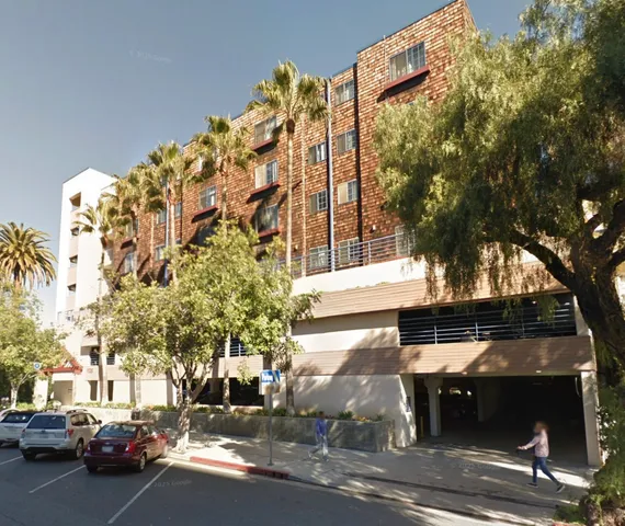 a view of a building with a cars park side of a road