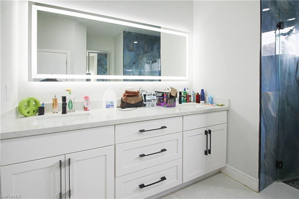 3902 4th Street Southwest Lehigh Acres, FL 33976 - Photo 27 of 34 Double vanity with integrated sinks, light-toned countertop, and white cabinetry featuring dark hardware