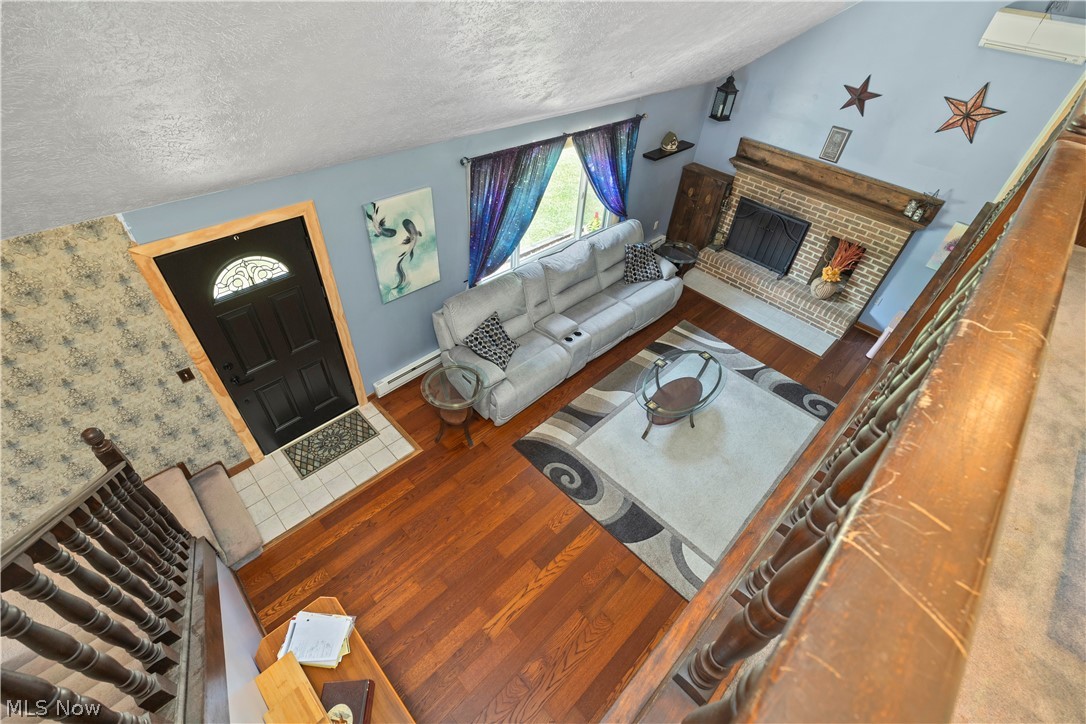 2565 Abbe Road North Sheffield Lake, OH 44054 - Photo 18 of 32 Living area featuring vaulted ceilings, wood-finish flooring, a brick fireplace with a wood mantle, and an arched entry door with decorative glass