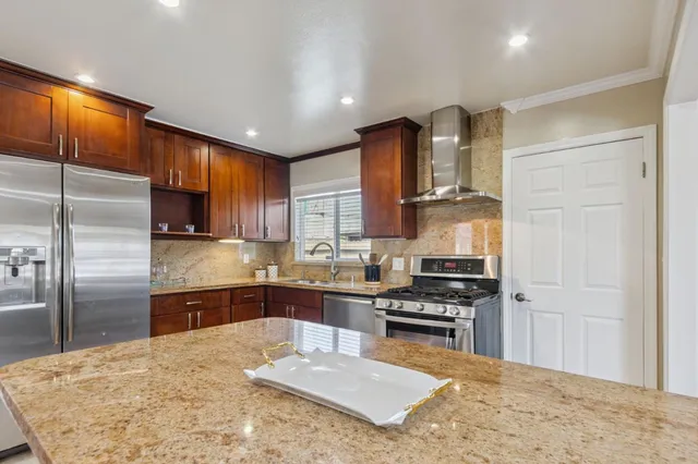 a kitchen with stainless steel appliances granite countertop a sink refrigerator and cabinets