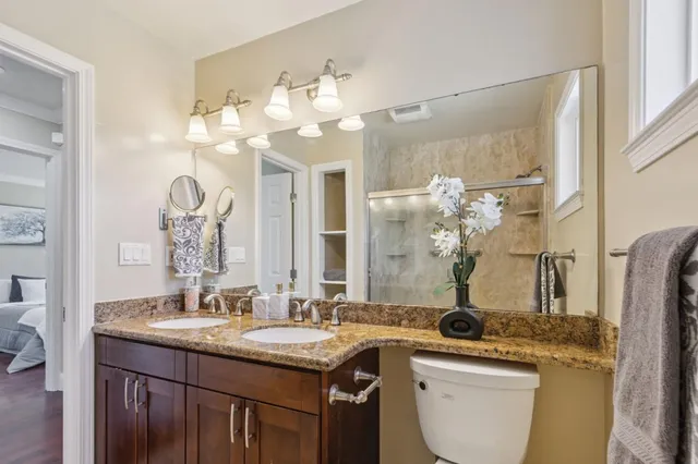 a bathroom with a granite countertop sink a toilet and a mirror