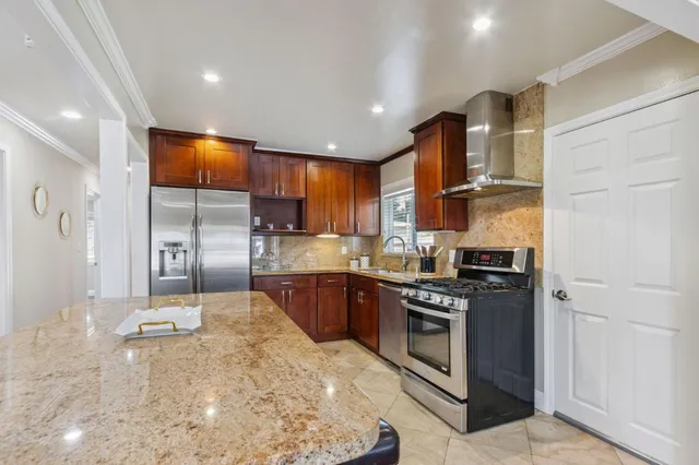 a kitchen with stainless steel appliances granite countertop a stove a refrigerator and a sink