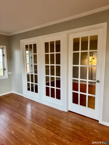 a view of an empty room with wooden floor and windows