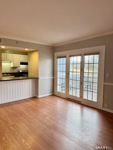 a view of an empty room with window and wooden floor
