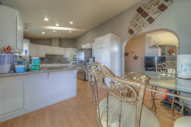 a kitchen with granite countertop white cabinets white stainless steel appliances with a sink and window