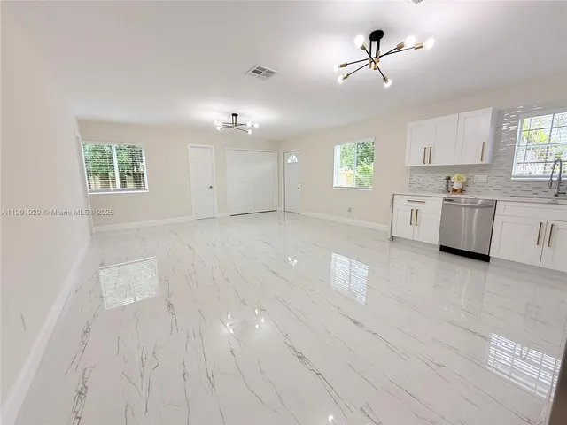 a kitchen with white cabinets and a large window