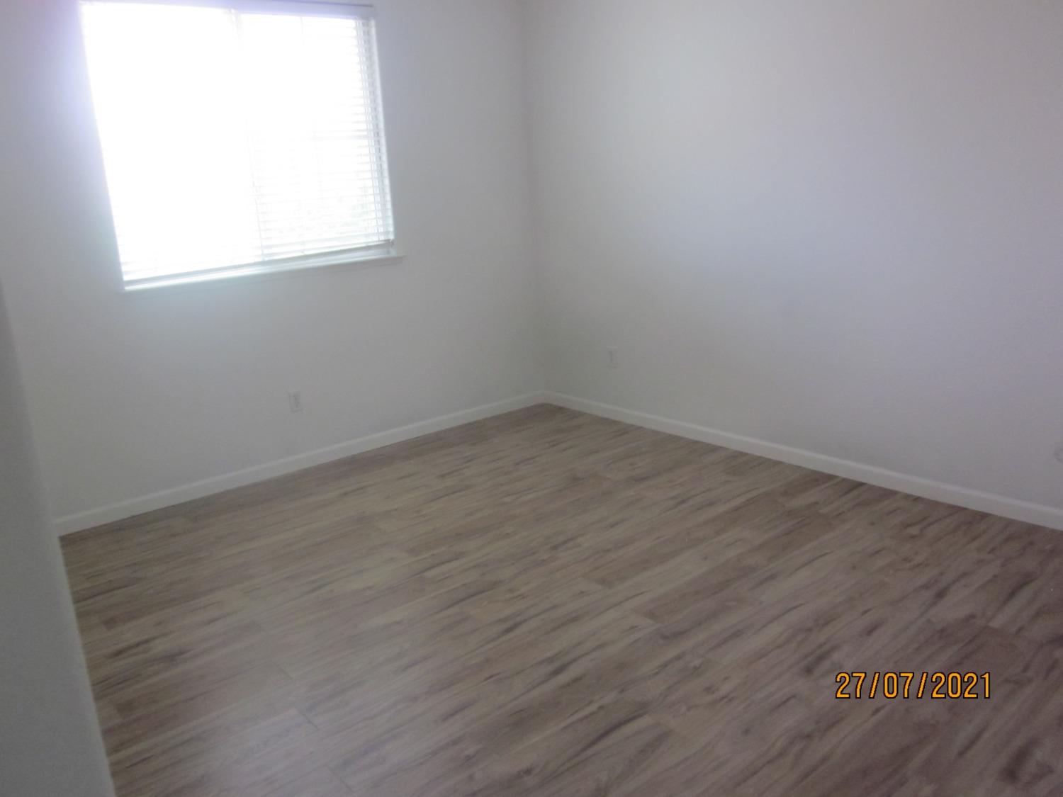 1360 Shady Lane, Unit 733 Turlock, CA 95382 - Photo 17 of 20 an empty room with wooden floor and windows