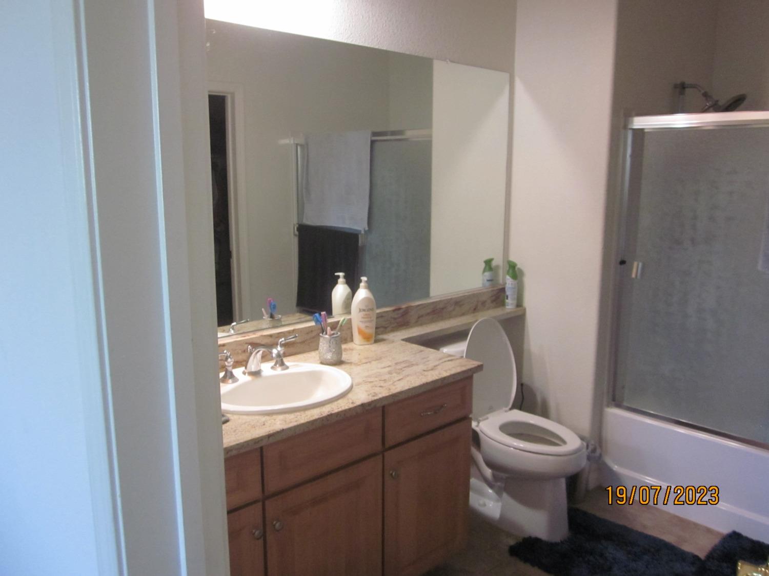 1360 Shady Lane, Unit 733 Turlock, CA 95382 - Photo 19 of 20 a bathroom with a granite countertop toilet sink and mirror