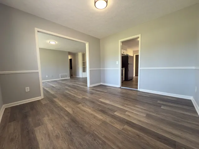 an empty room with wooden floor and mirror
