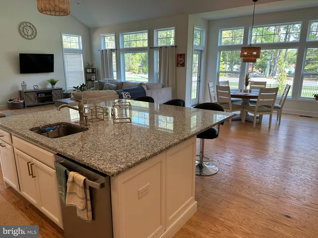 a kitchen with stainless steel appliances kitchen island granite countertop a dining table chairs and a refrigerator