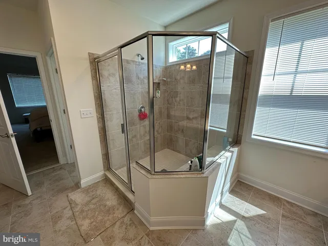 a bathroom with a tub shower sink and mirror