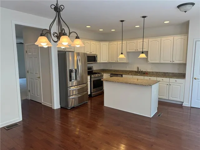 a kitchen with stainless steel appliances granite countertop a sink a stove a refrigerator and island with wooden floor