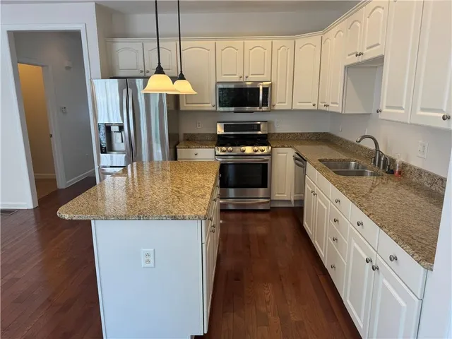 a kitchen with stainless steel appliances granite countertop a refrigerator a stove and a sink