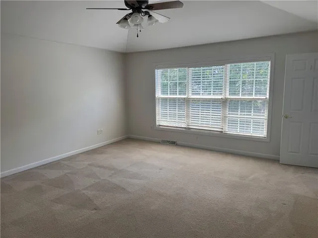 an empty room with a ceiling fan and a window