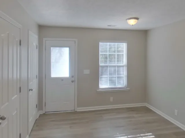 an empty room with wooden floor and windows