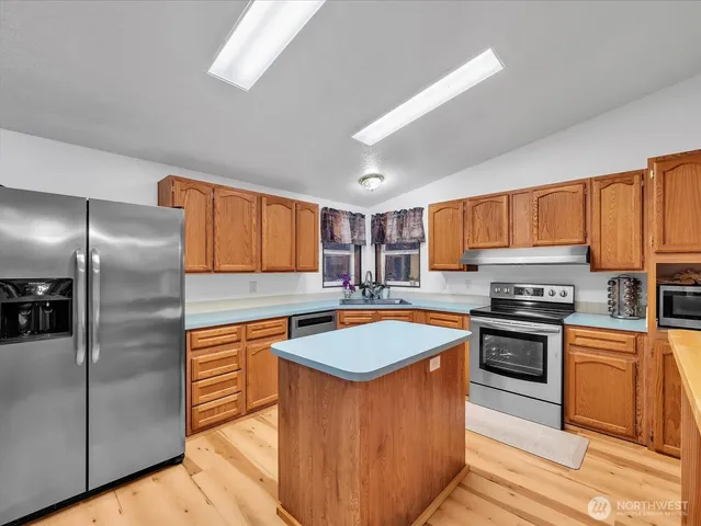a kitchen with stainless steel appliances granite countertop a sink stove refrigerator and cabinets