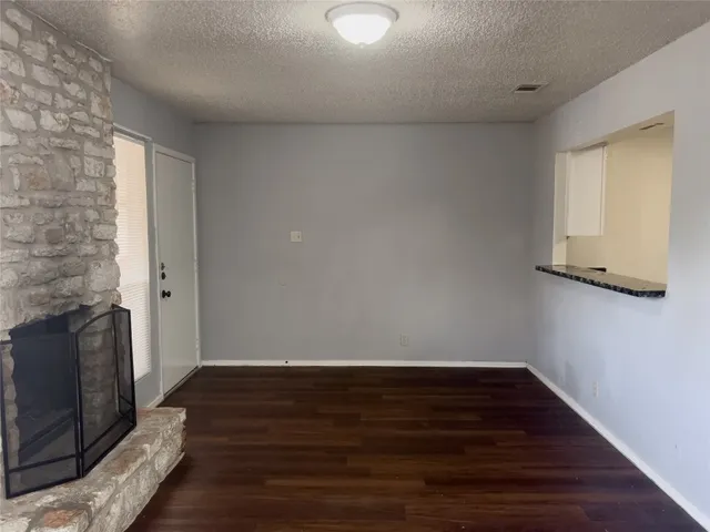 a view of an empty room with wooden floor and a fireplace