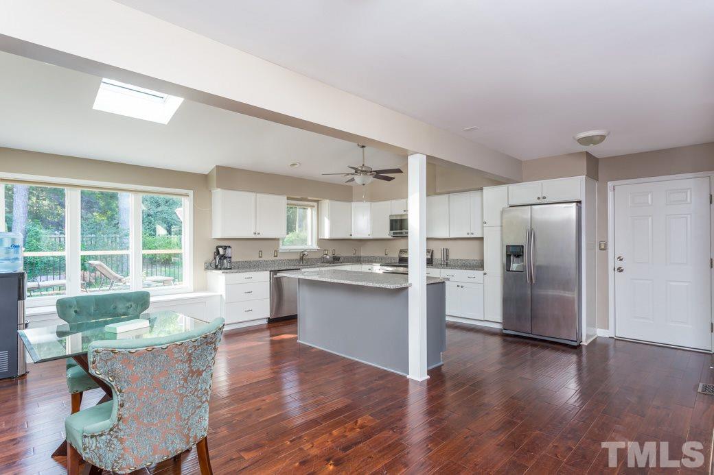 4213 Tolchester Place Raleigh, NC 27613 - Photo 4 of 25 a living room with stainless steel appliances kitchen island granite countertop a refrigerator a sink a stove and a wooden floors