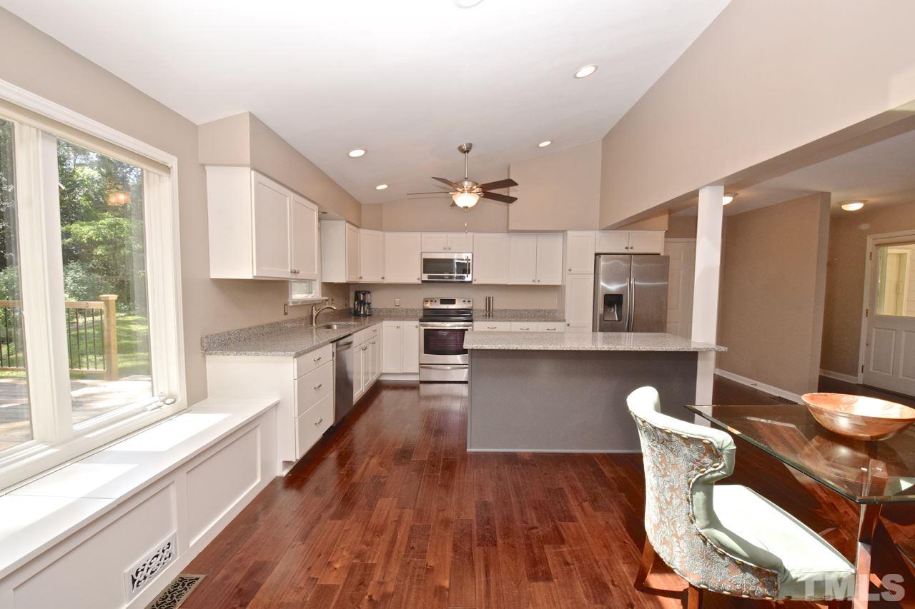 4213 Tolchester Place Raleigh, NC 27613 - Photo 5 of 25 a kitchen with stainless steel appliances wooden floors and white cabinets