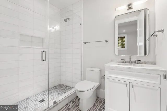 a bathroom with a granite countertop toilet a sink a mirror and shower