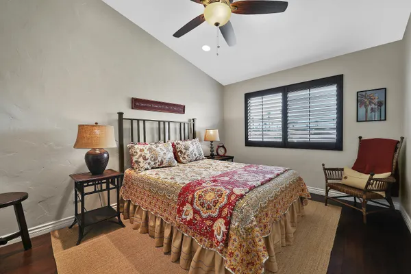 a bedroom with a bed a desk and chair with wooden floor