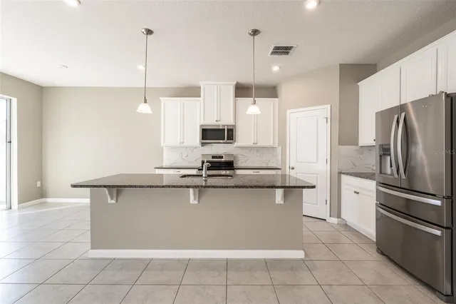 a kitchen with stainless steel appliances a sink a counter and chairs