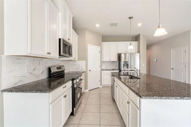 a large kitchen with granite countertop a stove top oven a sink a counter space and cabinets