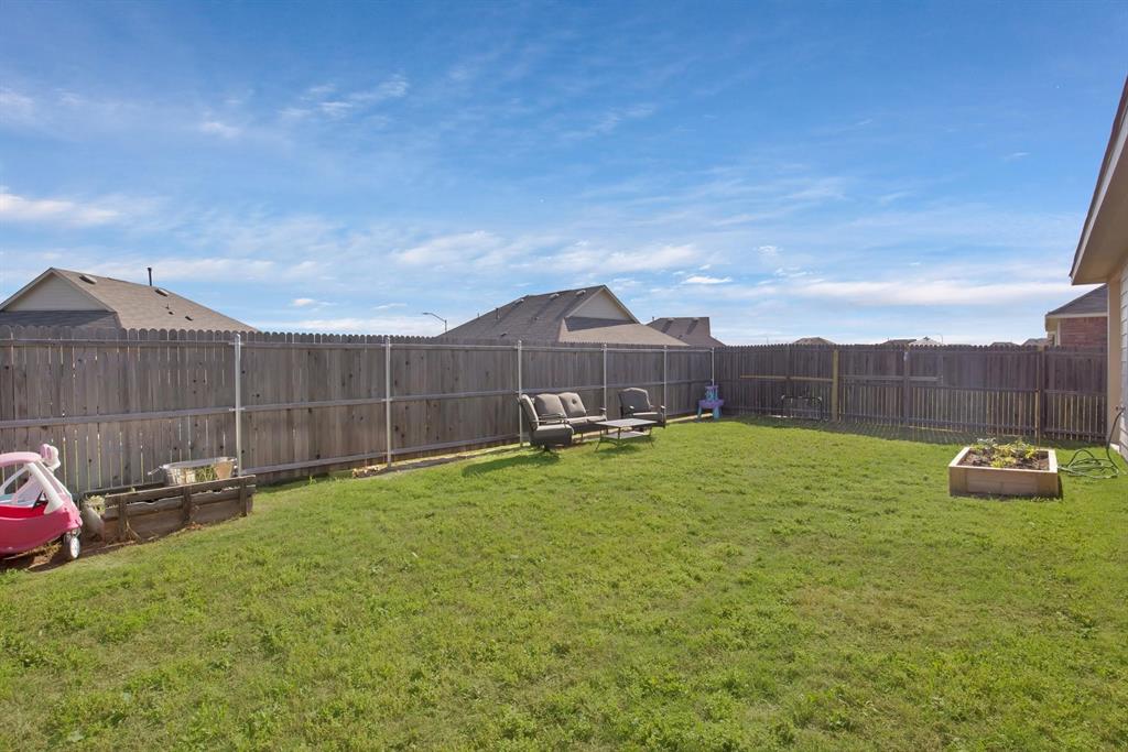 621 Ridgeback Trail Fort Worth, TX 76052 - Photo 18 of 22 Expansive backyard featuring a privacy fence, a raised garden bed, and a spacious lawn area