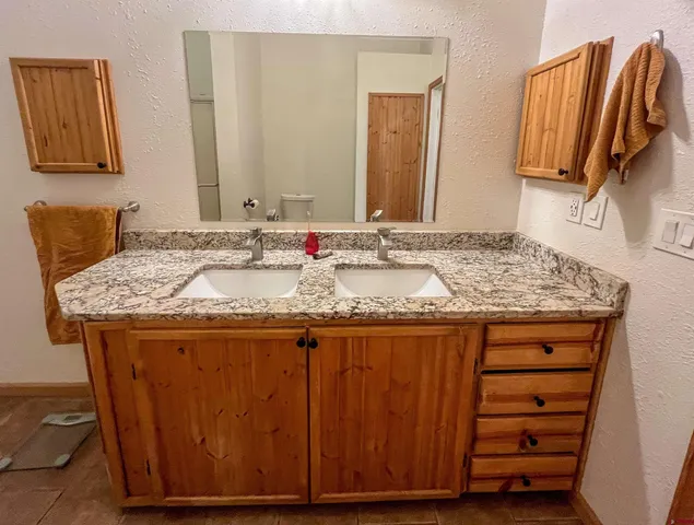 a bathroom with a granite countertop sink a mirror and shower
