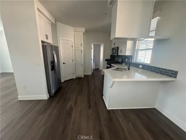 a hallway view with wooden floor and electronic appliances
