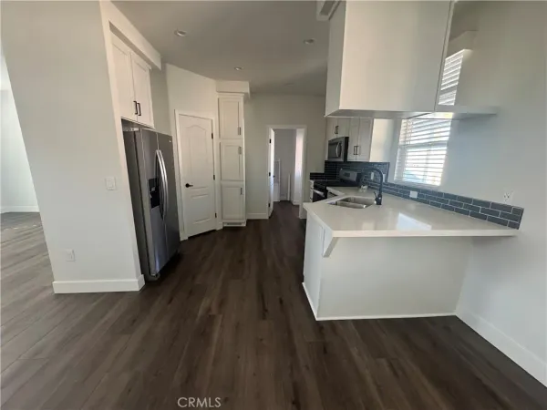 a hallway view with wooden floor and electronic appliances