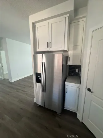 a view of a refrigerator in kitchen and white cabinets